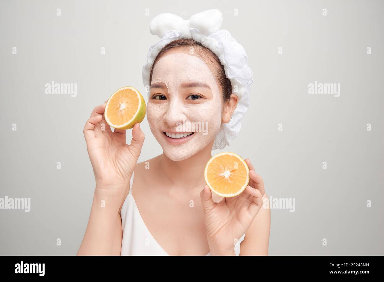 Junge Asiaten mit weißen Gesichtsmaske Ton und halten orange Stück. Stockfoto
