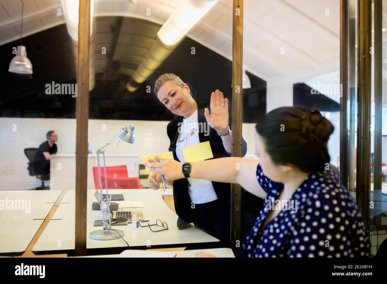 Weibliche Büroangestellte, die über Niesen-Wächter kommunizieren Stockfoto