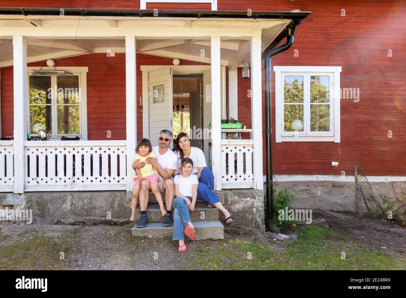 Eltern mit zwei Töchtern sitzen vor dem Haus Stockfoto