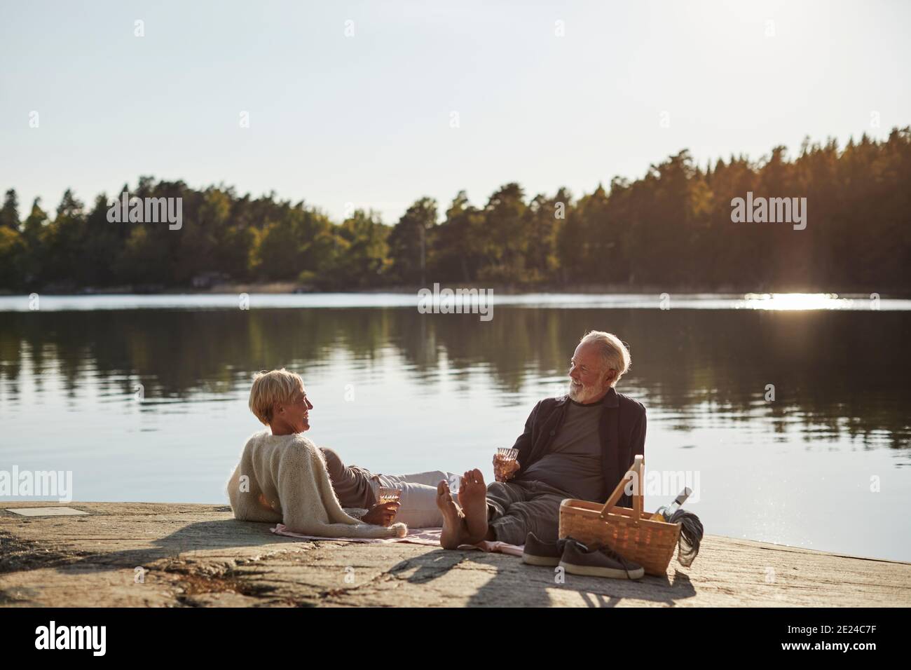 Lächelndes Paar beim Picknick am See Stockfoto