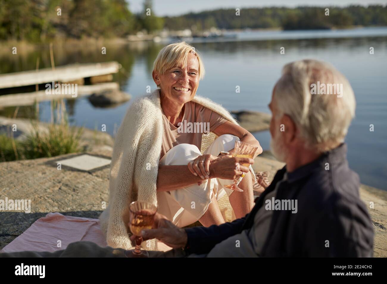 Lächelndes Paar beim Picknick am See Stockfoto