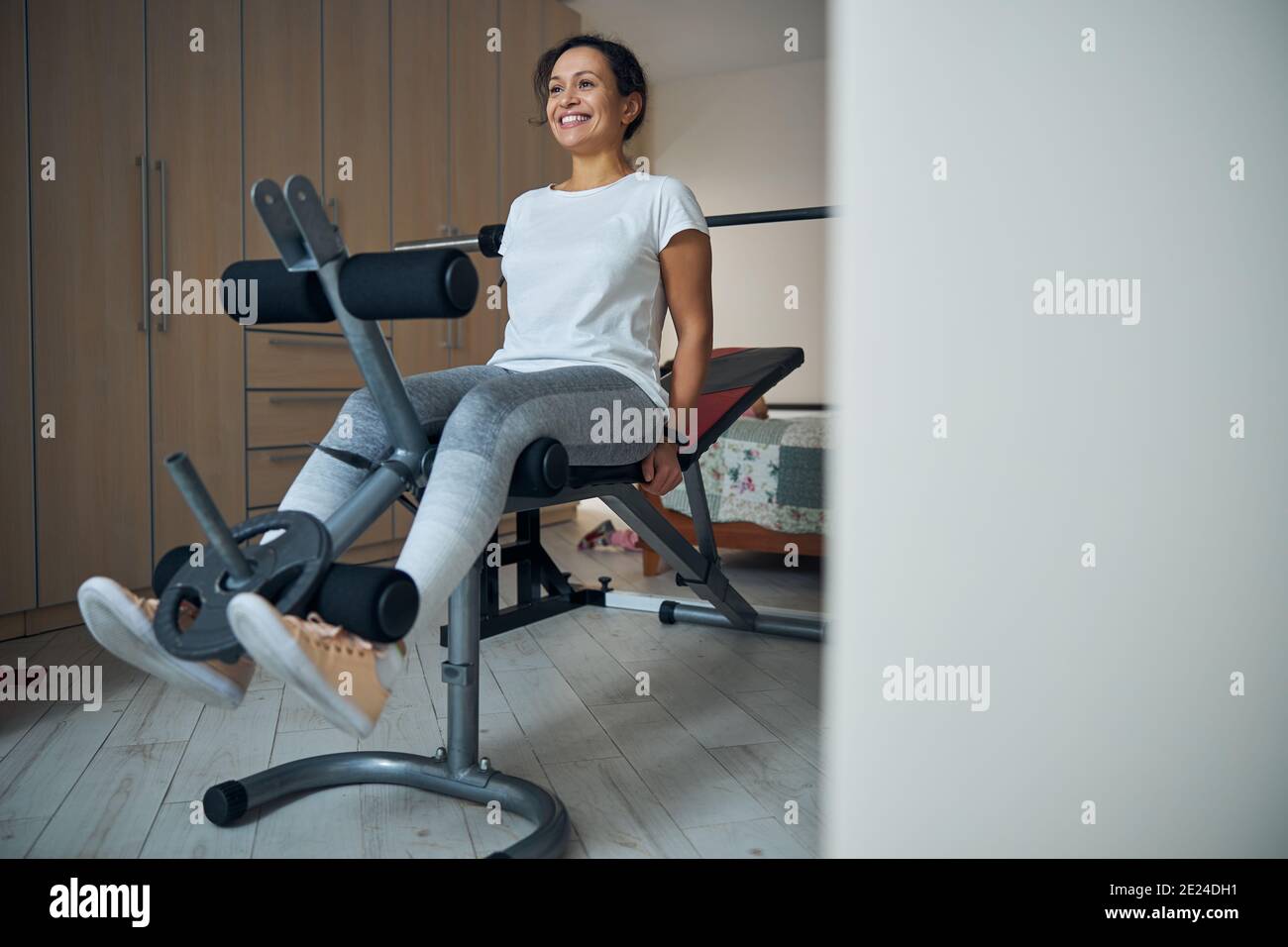 Fröhliche niedliche Sportlerin Durchführung der sitzenden Bein curl Stockfoto