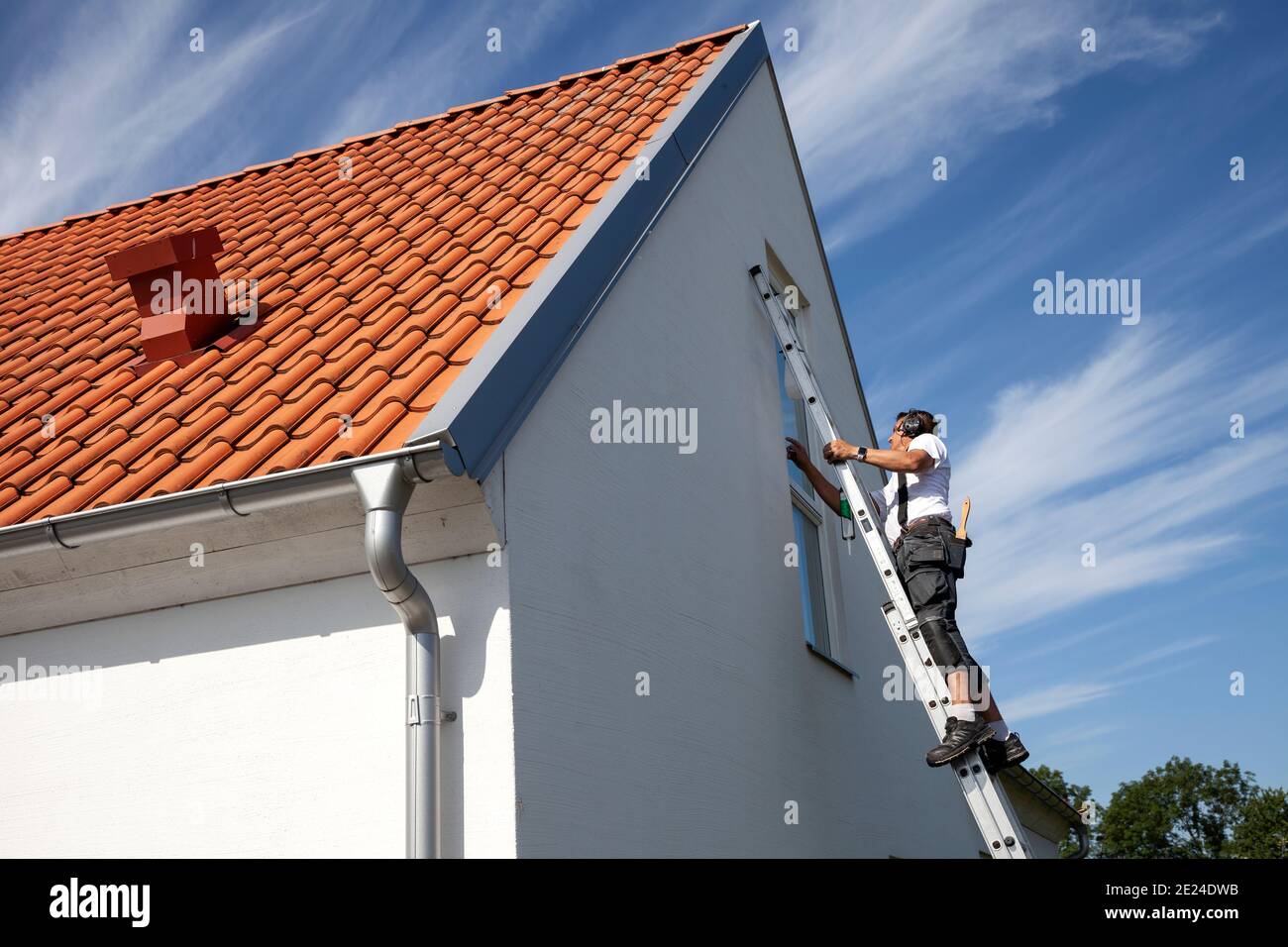 Mann auf der Leiter, der Hausreparaturen durchführt Stockfoto