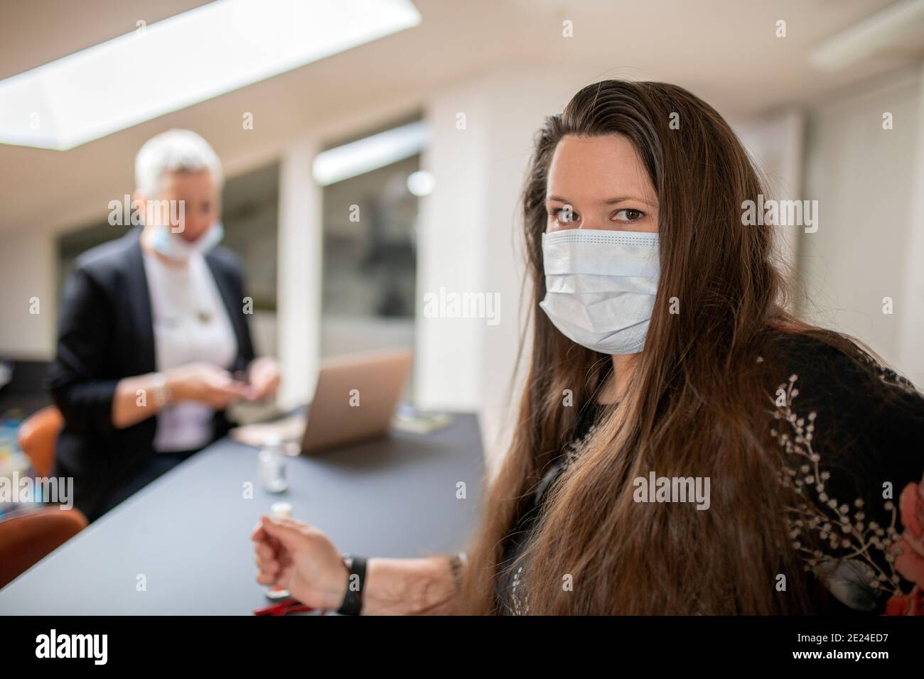 Frau im Büro trägt Gesichtsmaske Stockfoto