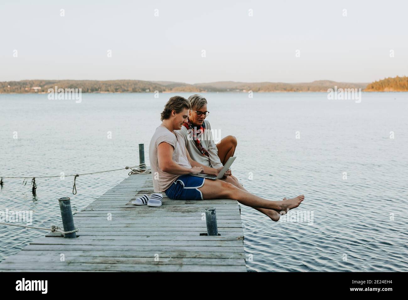 Mutter mit erwachsenem Sohn auf dem Steg und Blick auf den Laptop Stockfoto