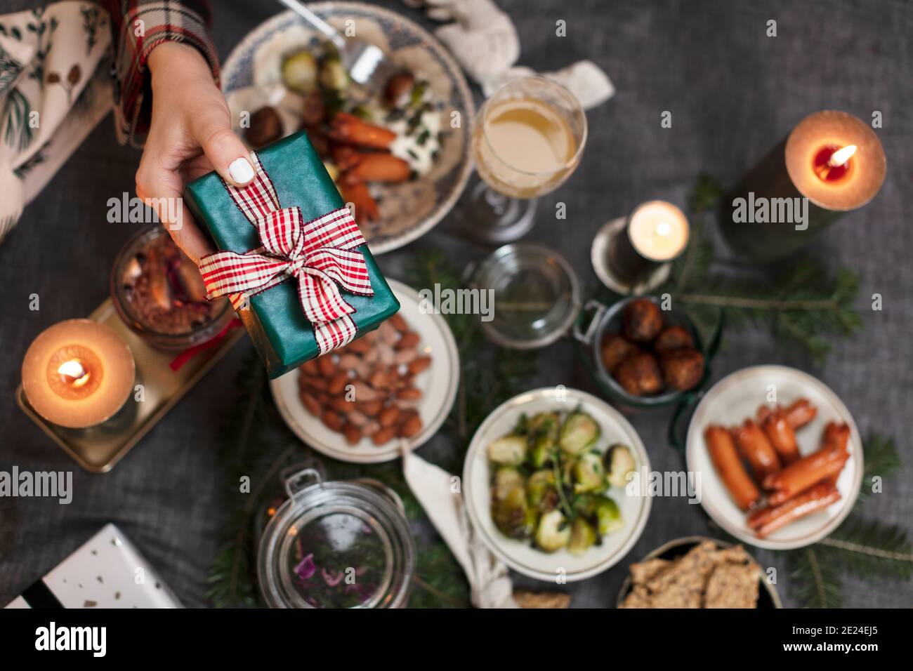 Hand halten Weihnachtsgeschenk über Tisch mit Essen Stockfoto