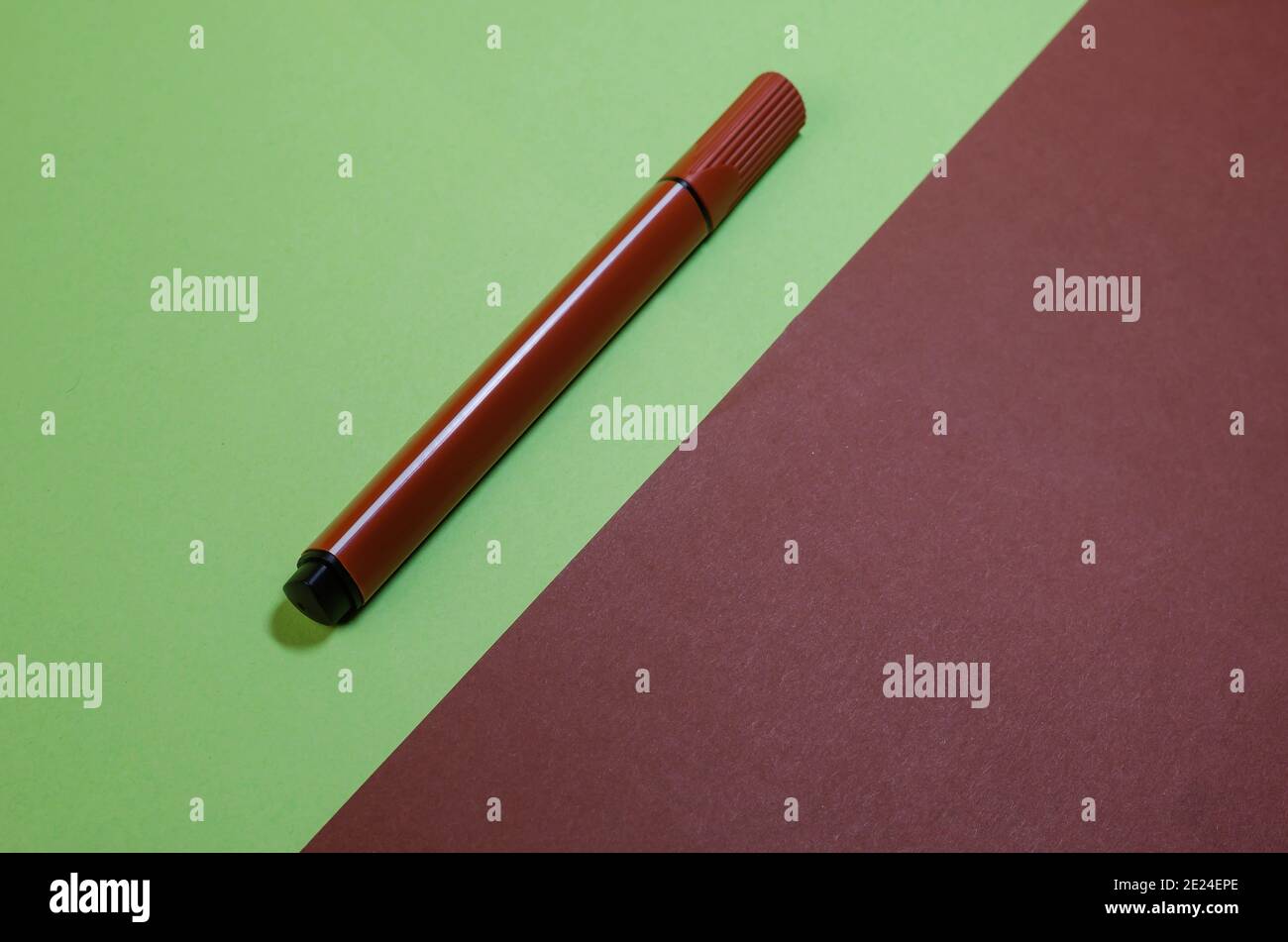 Kreative minimalistische Komposition mit braunem Filzstift auf zweifarbigem Hintergrund. Braun und Grün harmonisiert Farben Stockfoto