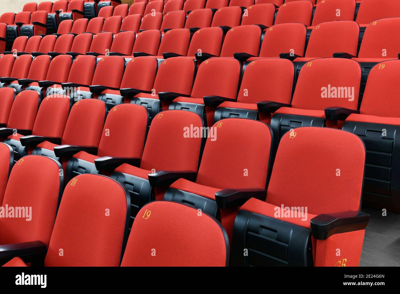 Reihen leerer roter Stühle in einem Theatersaal Nahaufnahme in einem schrägen Winkel in einer Unterhaltung Oder Konzept der darstellenden Kunst Stockfoto