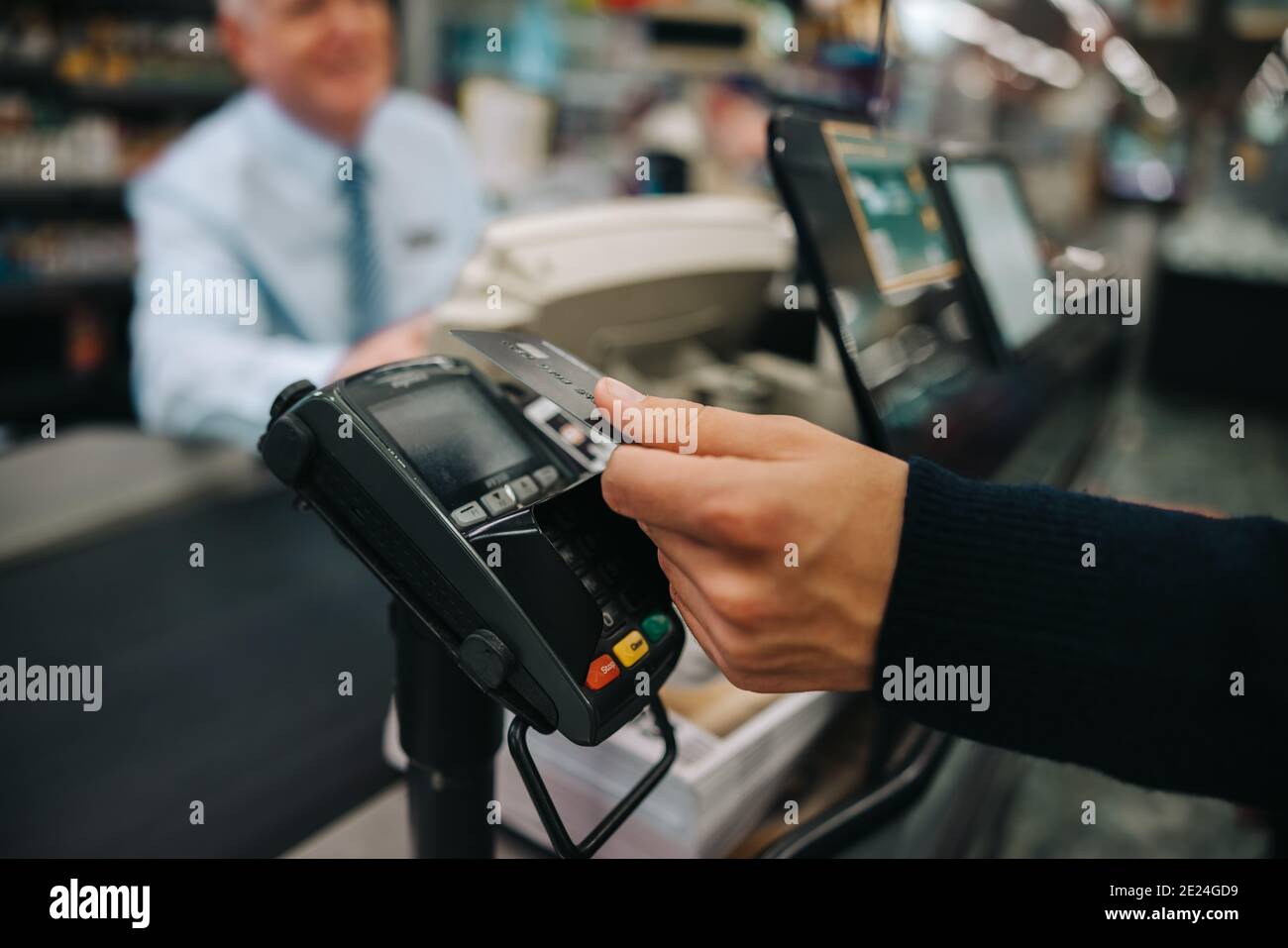 Nahaufnahme eines männlichen Kunden, der eine kontaktlose Zahlung mit seiner Kreditkarte im Lebensmittelgeschäft macht. Der Käufer zahlt für seinen Einkauf mit einer Kreditkarte. Stockfoto