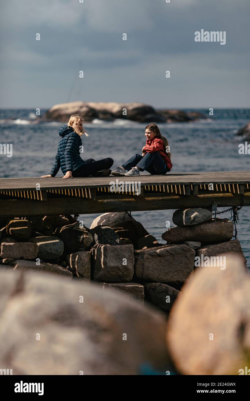 Mutter und Tochter sitzen auf dem Steg Stockfoto