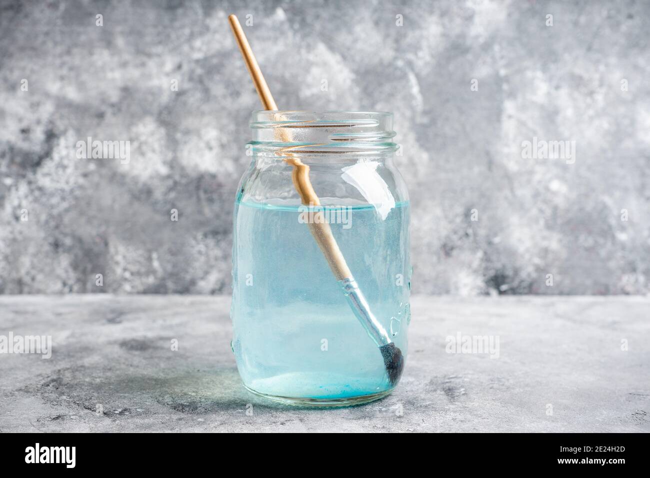 Künstlerische Pinsel in einem Glas mit Wasser auf dem grauen rustikalen Hintergrund. Interpreten-Tools. Selektiver Fokus. Stockfoto