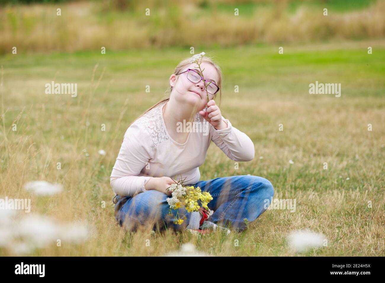 Lächelndes Mädchen auf der Wiese mit Wildblumen Stockfoto