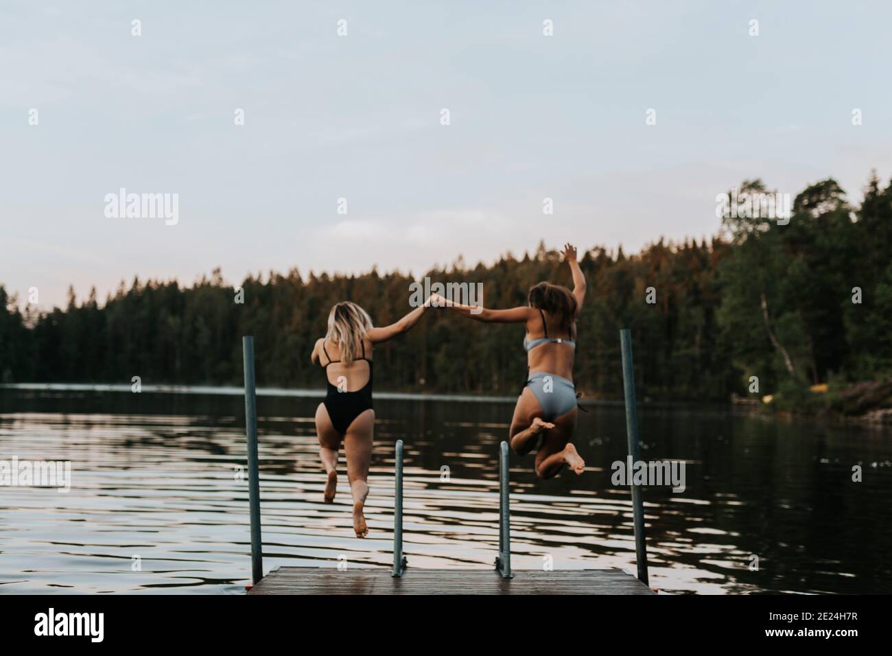 Frauen springen zusammen ins Wasser Stockfoto