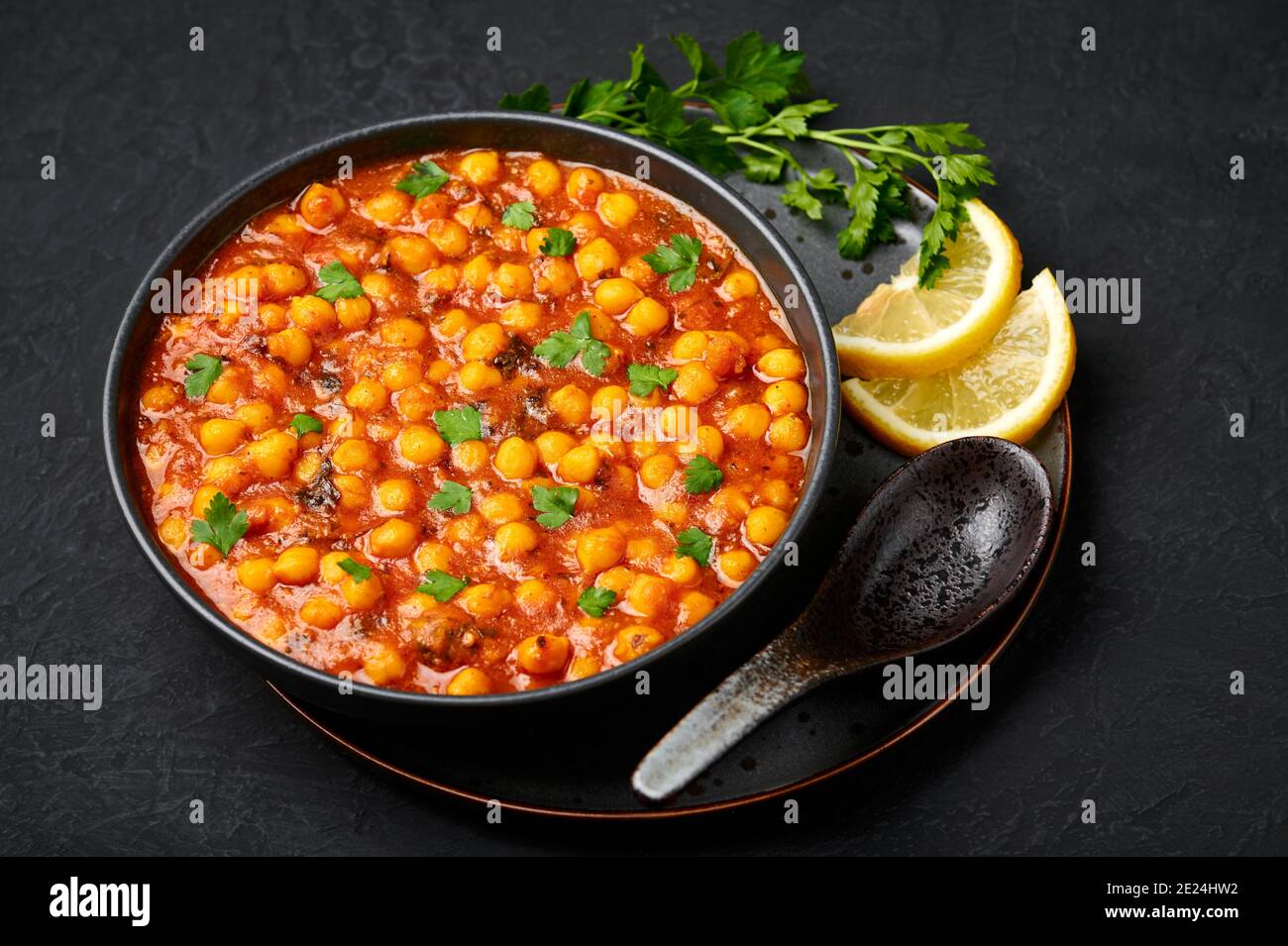 Chana Masala oder Chole in schwarzer Schale auf dunkler Schieferplatte. Indische Küche Gemüse Kichererbsen Currygericht. Asiatische würzige vegetarische Speisen und Gerichte. Stockfoto