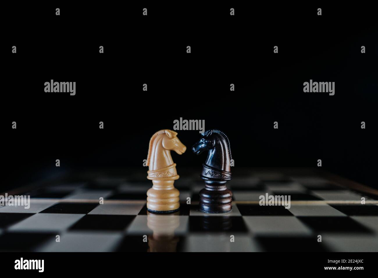 Zwei Pferde-Stücke einander gegenübergestellt auf einem Schachbrett in einem dunklen Stil. Interracial Liebe Konzept. Selektiver Fokus Stockfoto