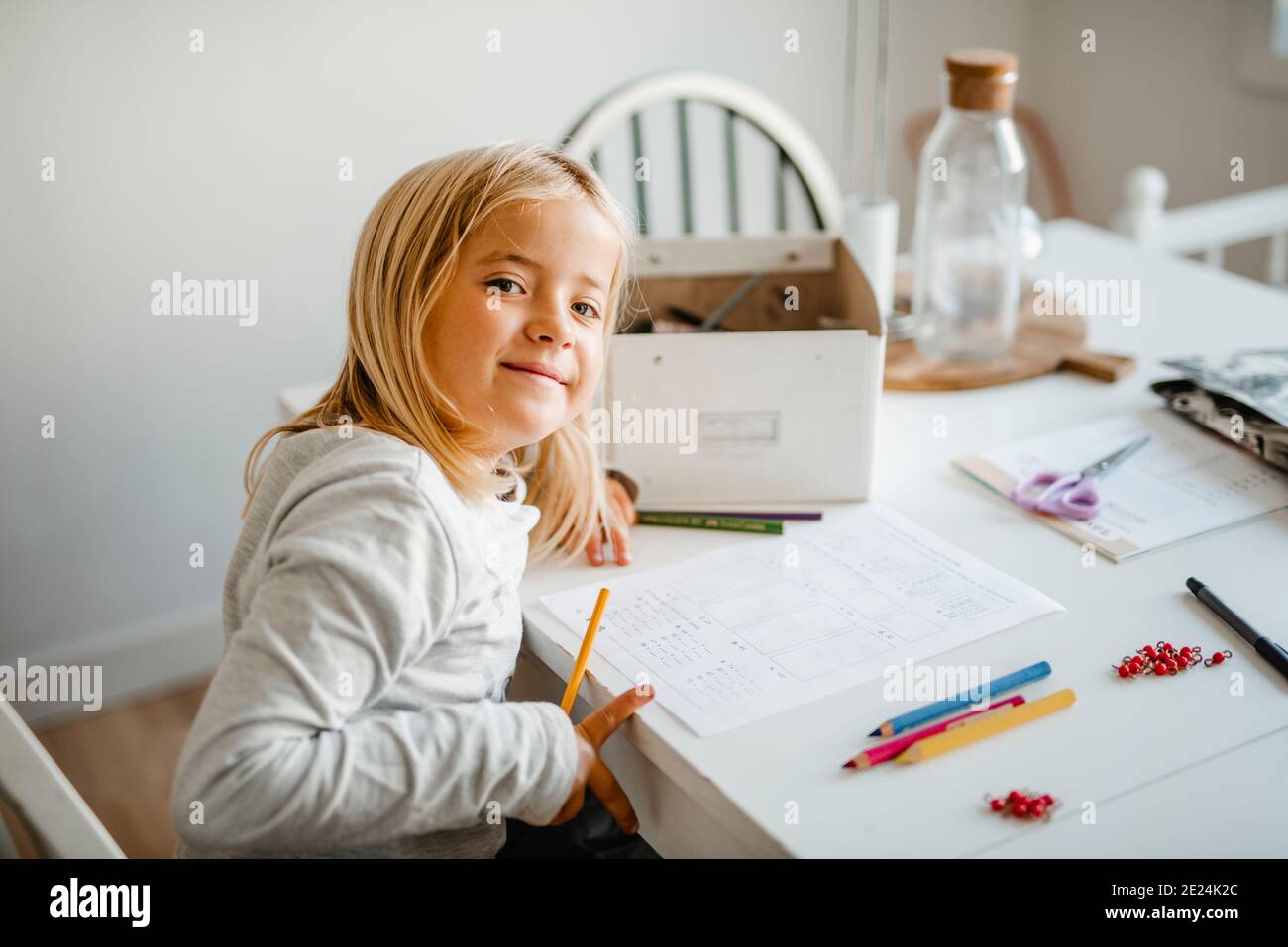 Lächelndes Mädchen zu Hause Hausaufgaben machen Stockfoto