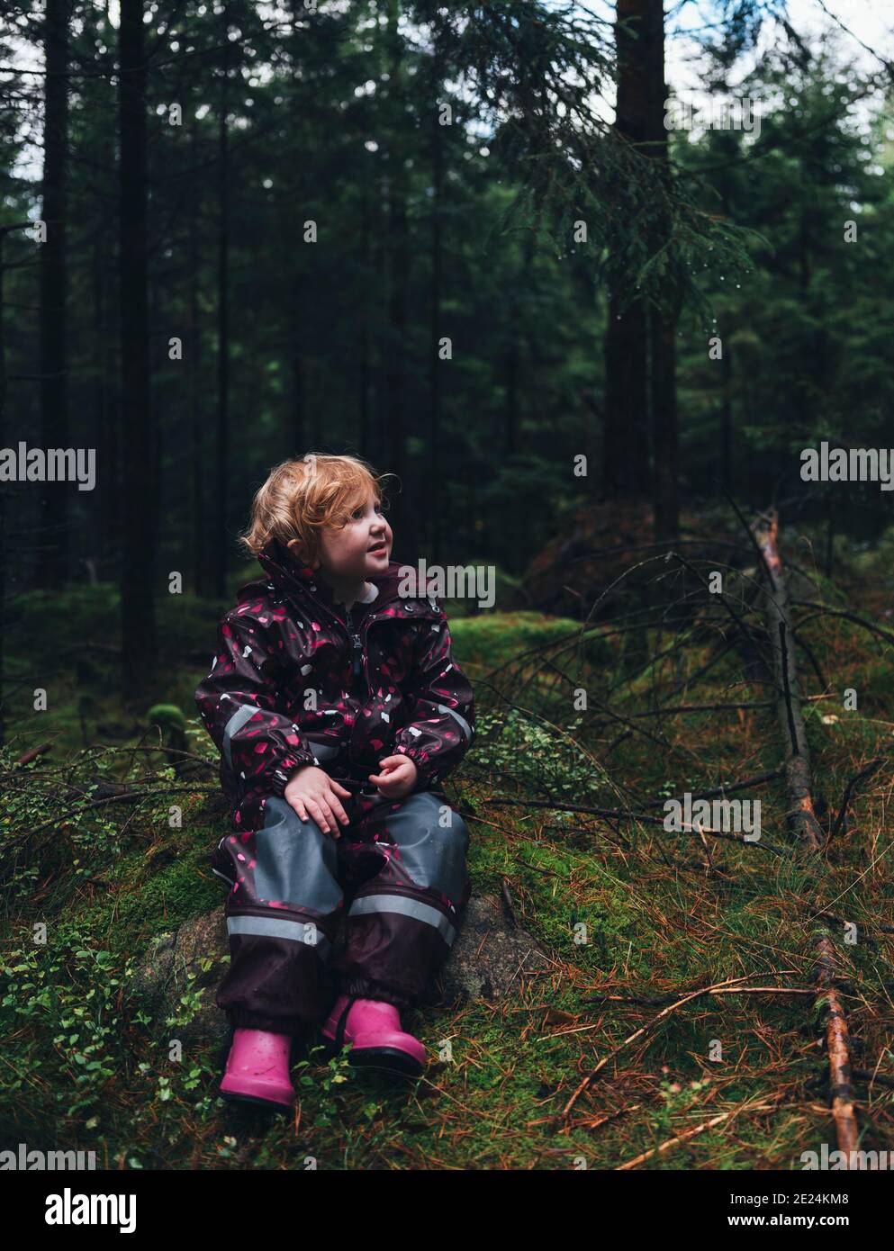 Kleinkind Mädchen sitzt im Wald Stockfoto