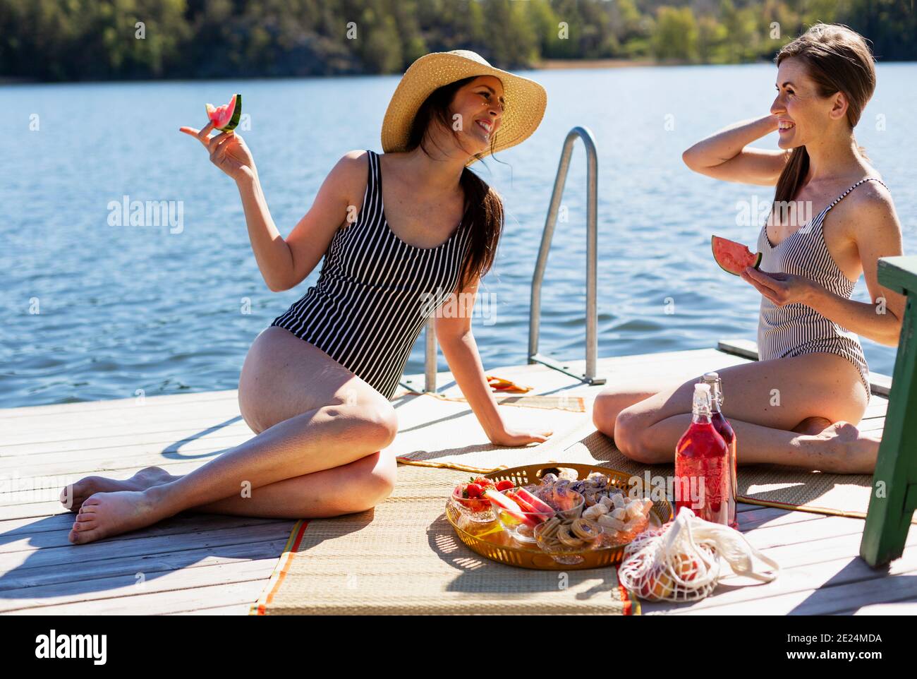 Glückliche Freundinnen beim Picknick auf dem Steg Stockfoto