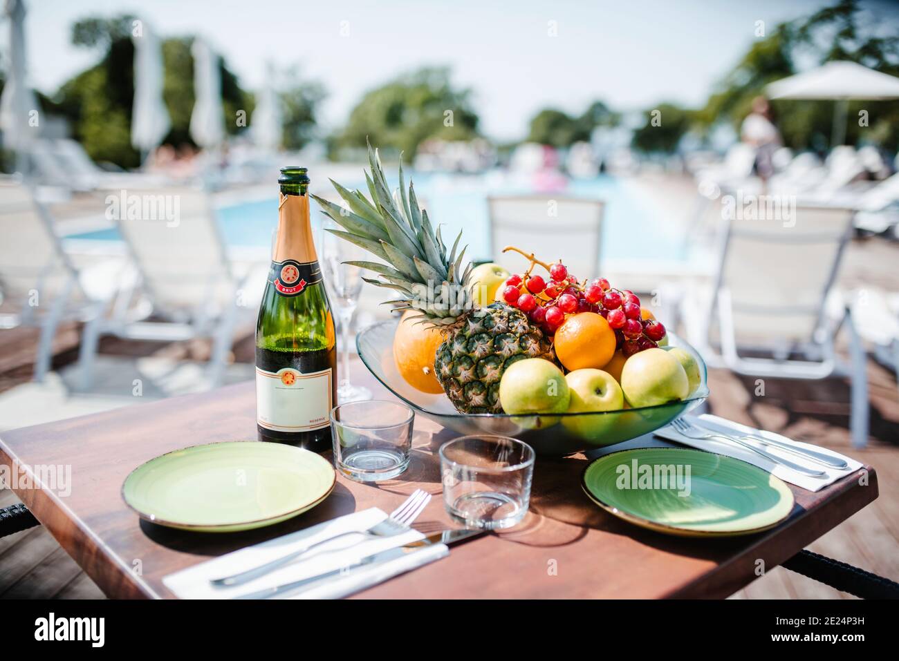Tisch-Set für zwei mit Champagner-Flasche und Schüssel Früchte Stockfoto