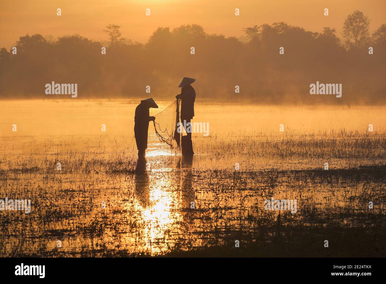 Silhouette von zwei Fischern werfen Fischernetze bei Sonnenuntergang, Thailand Stockfoto