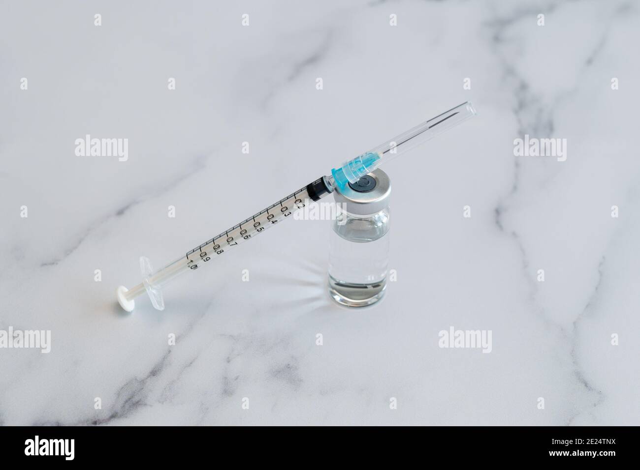 Medizinische Spritze und Nadel für die Injektion von Unterspritzung auf einer Arbeitsplatte aus Marmor. Spritze und Nadel sind verschlossen. Stockfoto