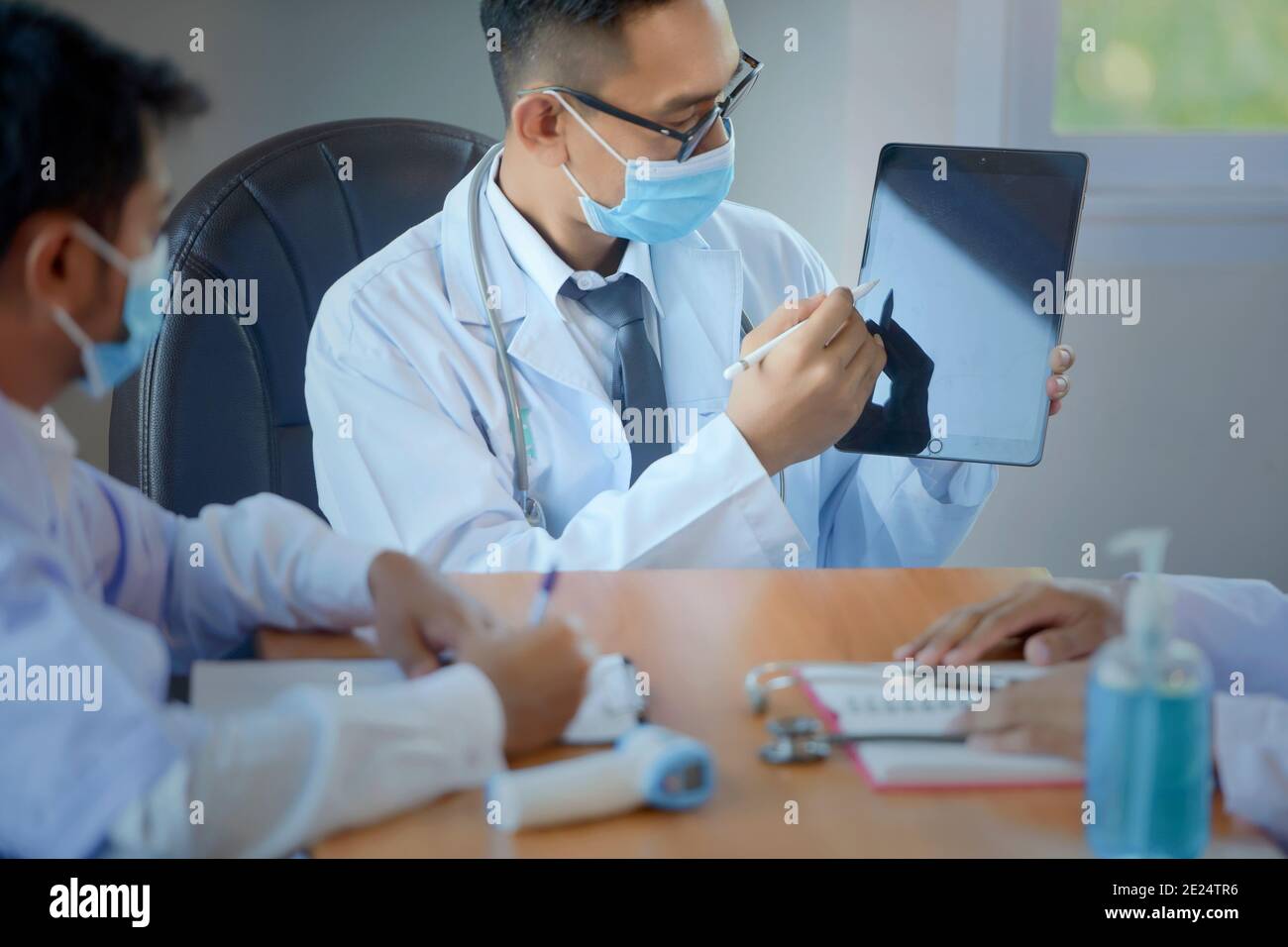 Drei Ärzte sitzen in einem Büro mit einer Sitzung, Thailand Stockfoto