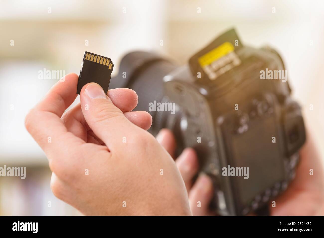 Hand holdnig SD-Speicherkarte, DSLR im Hintergrund Stockfoto