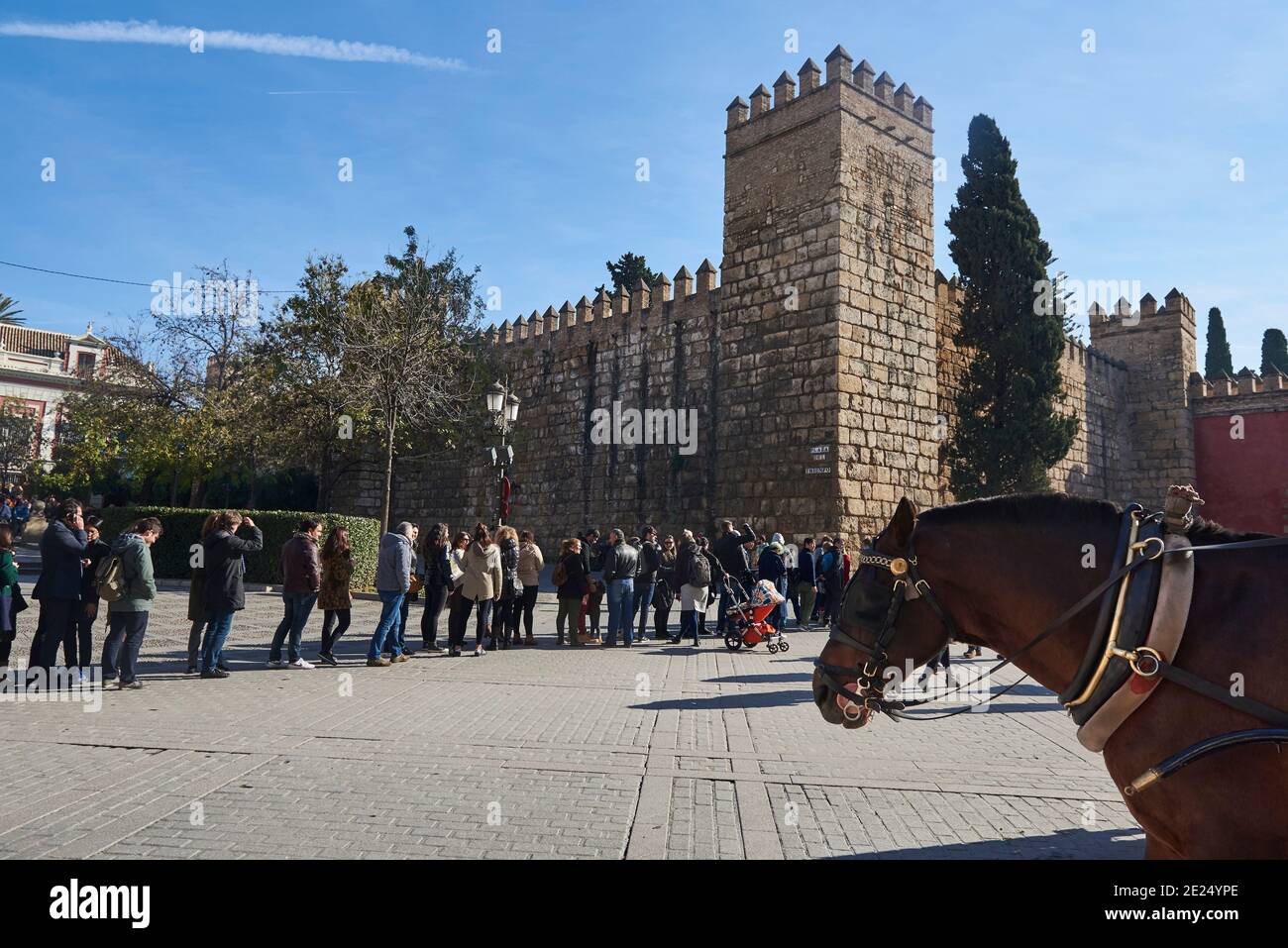 Sevilla, Andalusien, Spanien, Europa. Pferdekutsche und Blick auf das Löwentor im Real Alcazar von Sevilla und Reihe von Menschen, die darauf warten, einzutreten Stockfoto