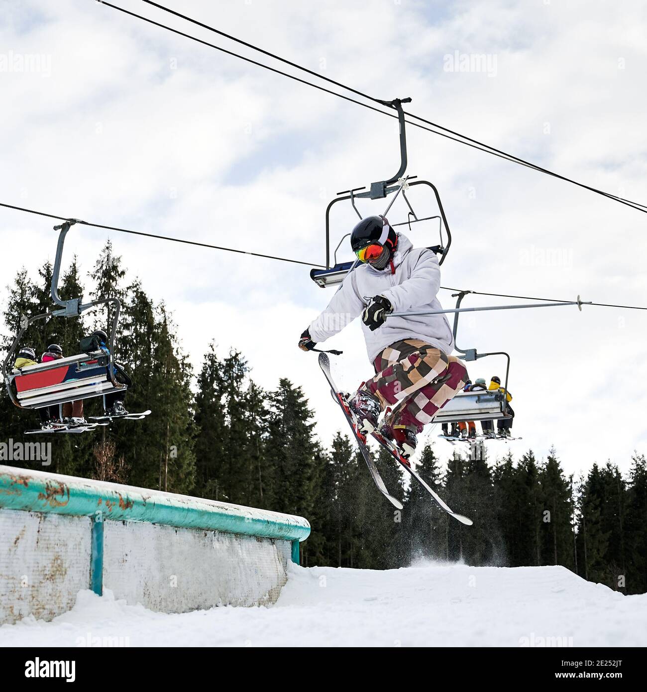 Skispringer beim Sprung in hoch im Skigebiet. Sessellift im Hintergrund. Winter Arten von Sport. Konzept des Extremsports Stockfoto