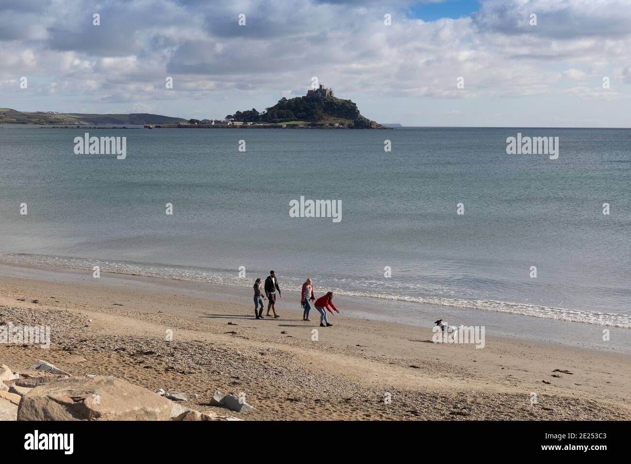 Hundewanderer, die mit ihren Hunden spazieren gehen und am Mount's Bay Beach in Cornwall schwimmen Stockfoto