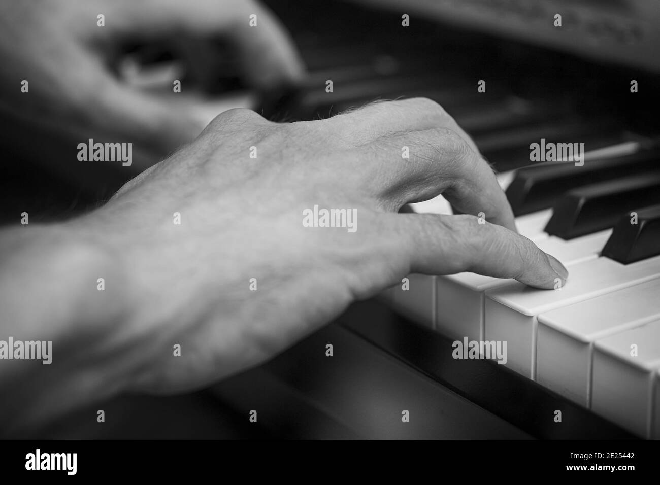Mann, der auf einem digitalen Klavier spielt. Schwarzweiß-Bild. Stockfoto