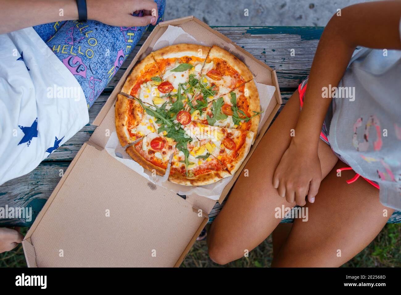 Zwei Mädchen im Teenageralter sitzen draußen mit Pizza Stockfoto