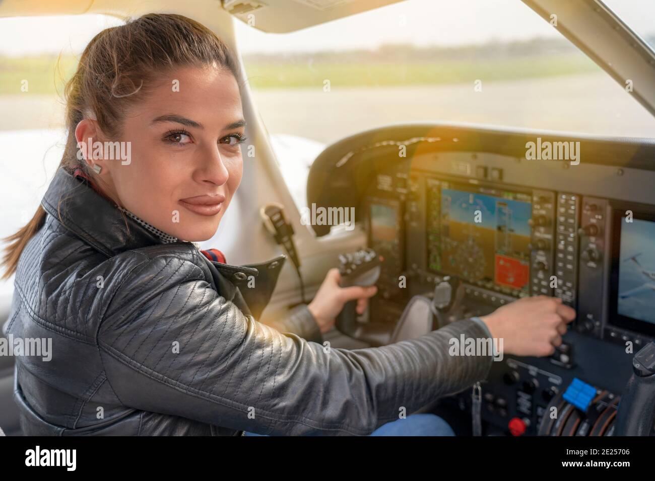 Schöne lächelnde Frau Pilot sitzt in der Kabine der modernen Flugzeuge. Porträt einer Pilotin im Cockpit der leichten Flugzeuge. Stockfoto