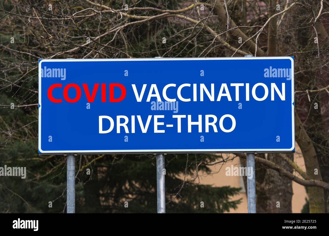 Covid-19 Impfung Drive-Thru-Konzept. Blaues Straßenschild mit Hinweis auf Durchfahrimpfstelle. Fotobearbeitung. Stockfoto