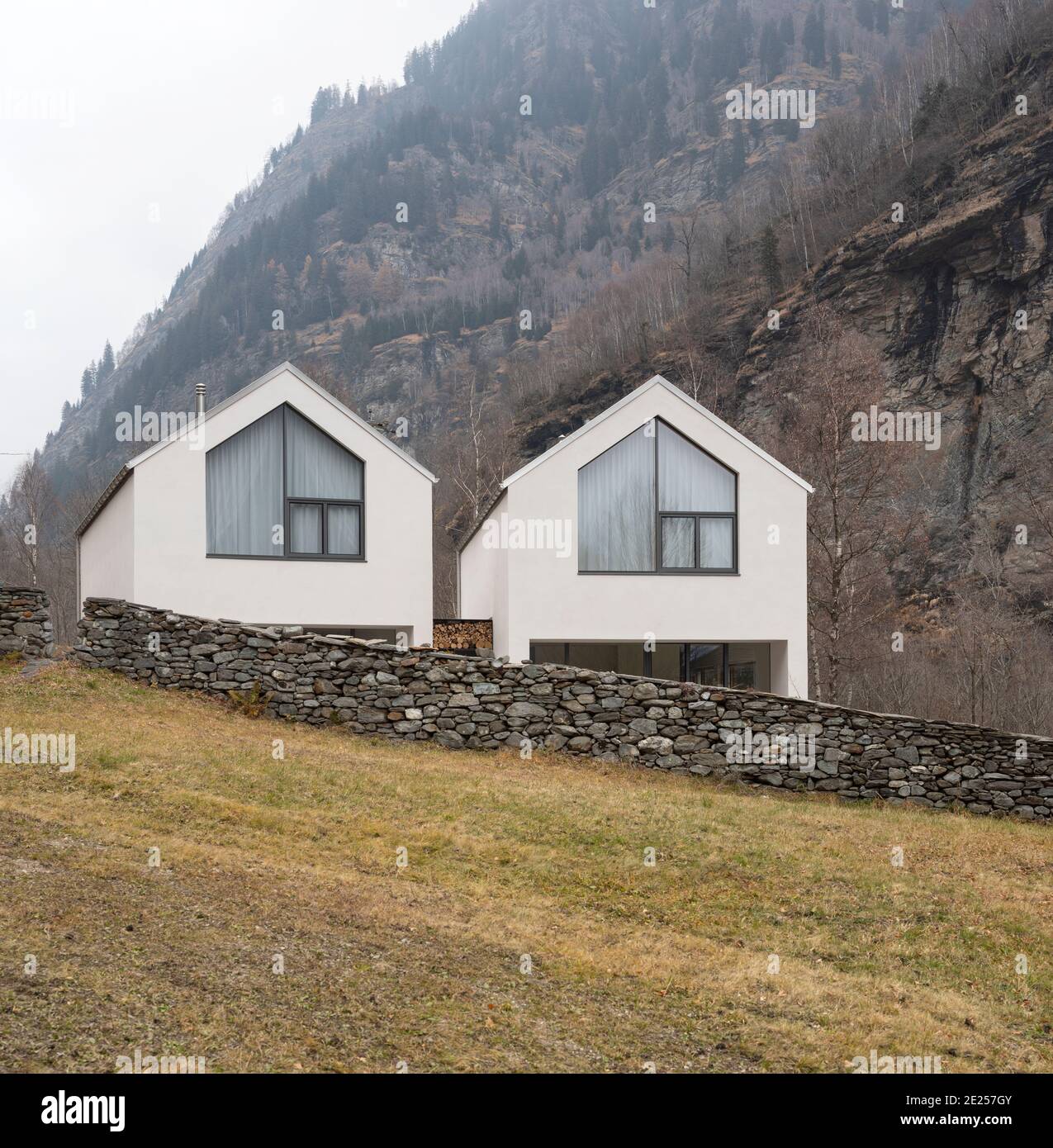 Weißes Haus umgeben von Natur, Wald und Nebel im Winter. Gebäude im schweizer Tal. Niemand drinnen Stockfoto