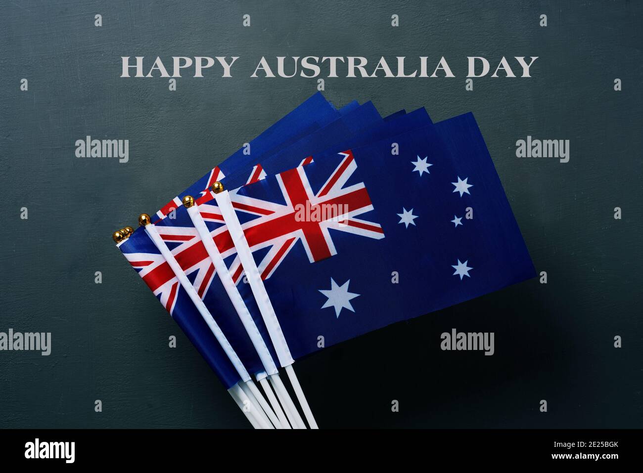 Nahaufnahme einiger australischer Flaggen und Text Happy australia Tag auf einem dunkelgrünen Hintergrund Stockfoto