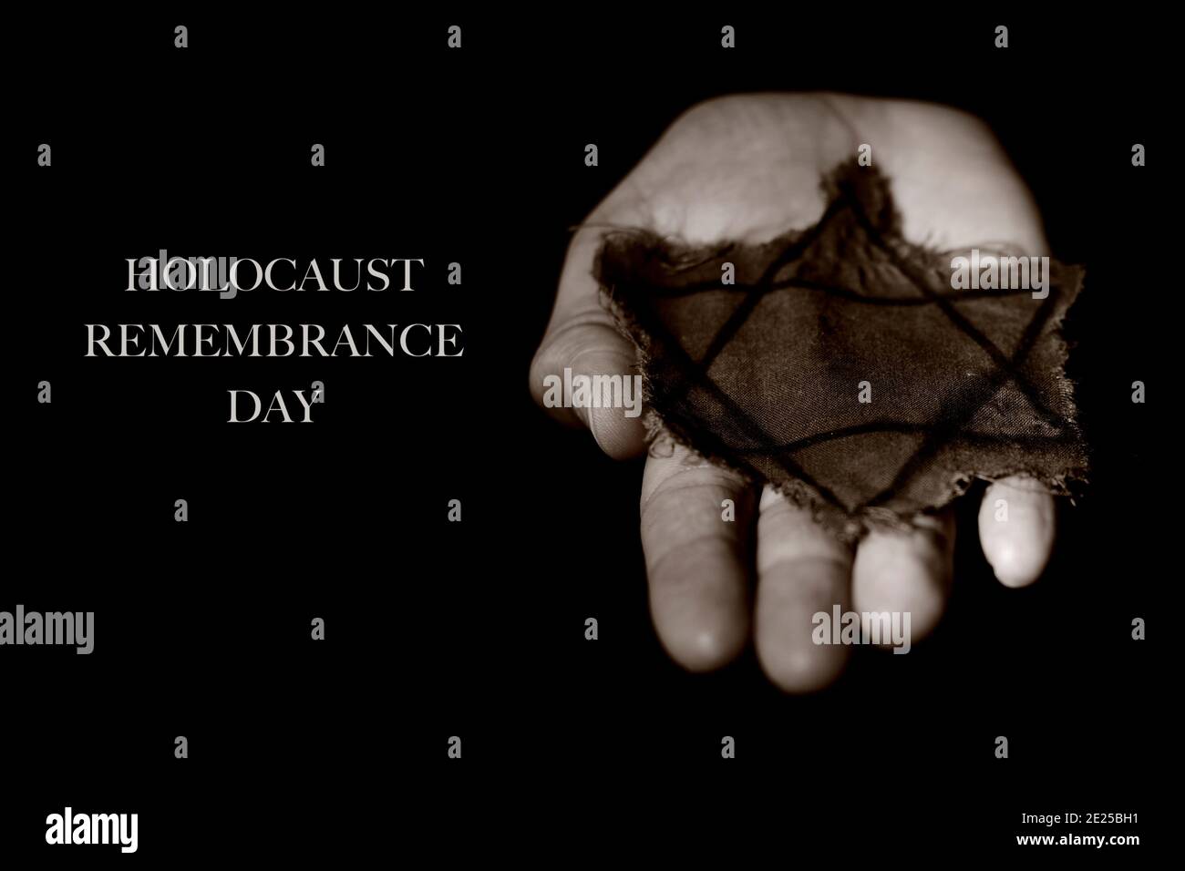 Nahaufnahme des davidsterns in einem alten und zerlumpten Abzeichen auf der Hand eines Mannes und der Text Holocaust-Gedenktag auf schwarzem Hintergrund Stockfoto