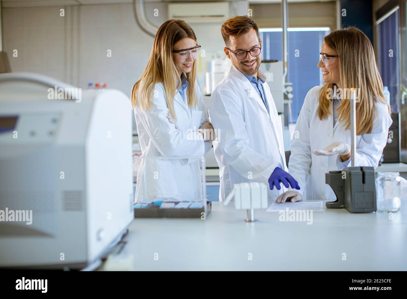 Gruppe von jungen Forschern in schützenden Arbeitskleidung stehen in der Labor und Analyse von flüssigen Proben an Ionenchromatographie-Geräten Stockfoto