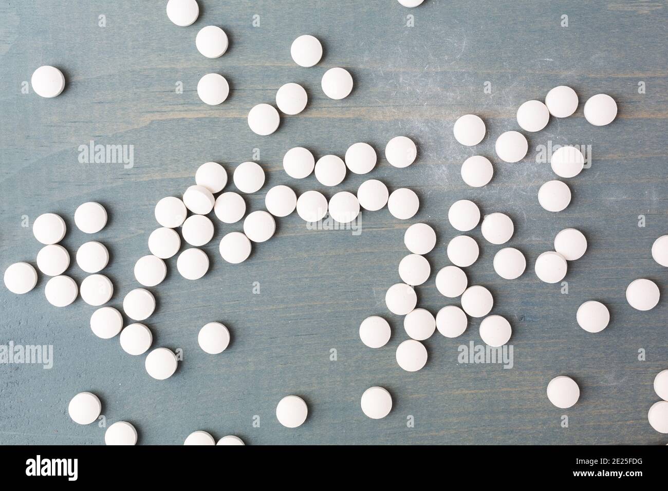 Draufsicht auf mehrere Vitamin D Tabletten auf einer blau lackierten verblassten Tischplatte. Stockfoto