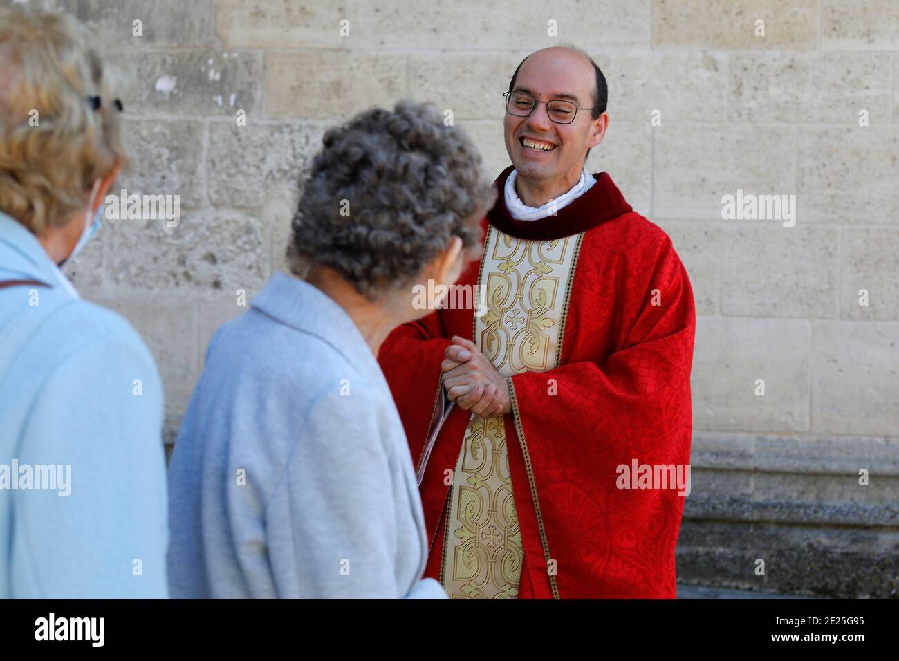 Priester grüßt die Gemeindemitglieder nach der Pfingstmesse in der Kirche des hl. Nikolaus, Beaumont-le-Roger, Frankreich Stockfoto
