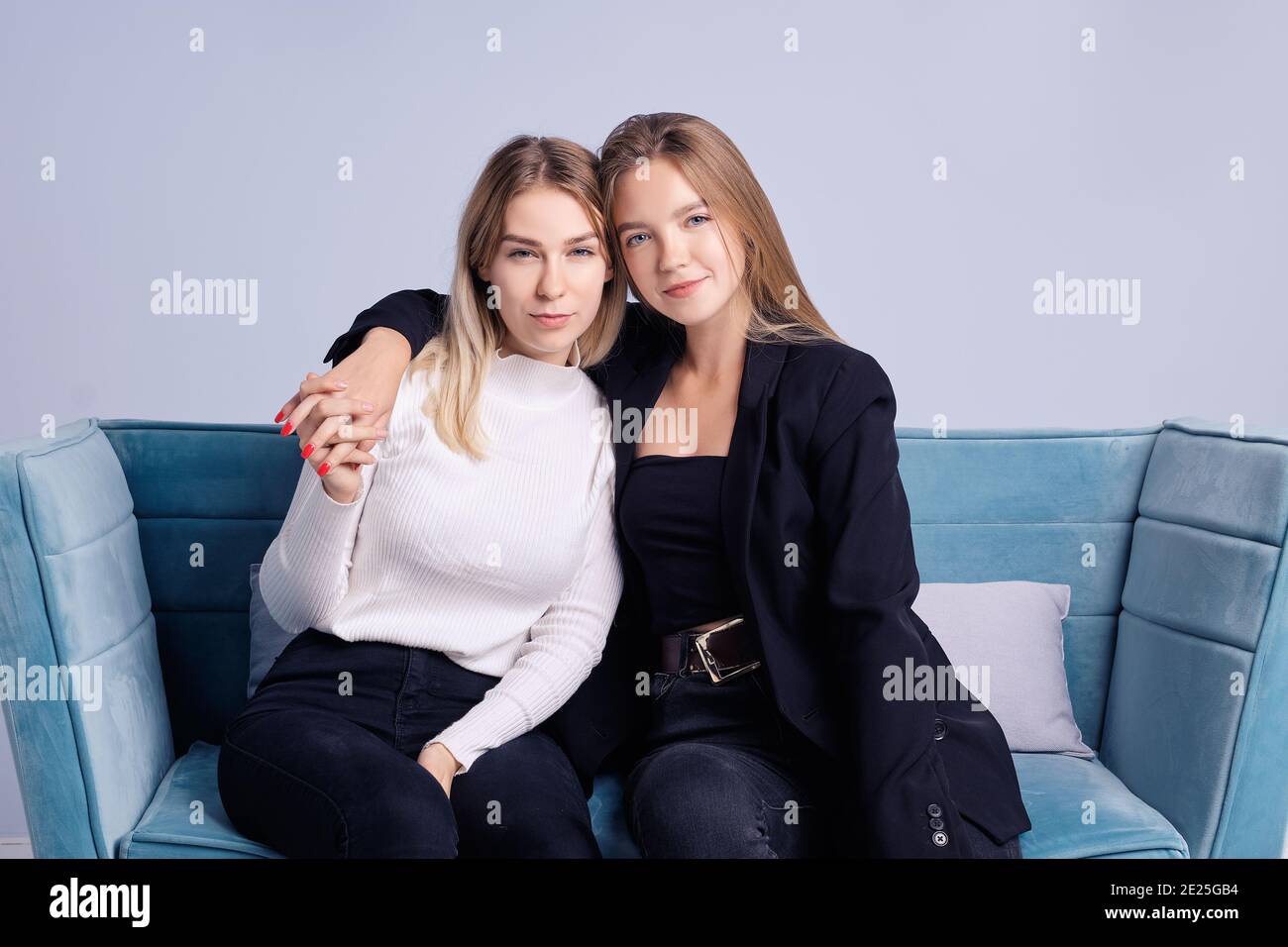 Zwei Mädchen, die sich umarmen. Sie sitzen auf der Couch zu Hause. Sie werden in einer guten Stimmung. Sie sind glücklich miteinander. Stockfoto