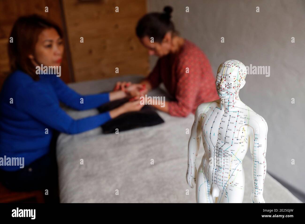 Traditionelle chinesische Medecine. Praktiker überprüft Puls der jungen Frau, um Krankheit zu definieren. Ein männliches Modell mit markierten Akupunkturpunkten. Frankreich. Stockfoto