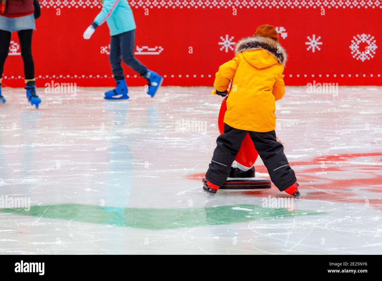 Im Winter, an einem frostigen Tag auf der Eisbahn, gehen Kinder Schlittschuhlaufen. Stockfoto