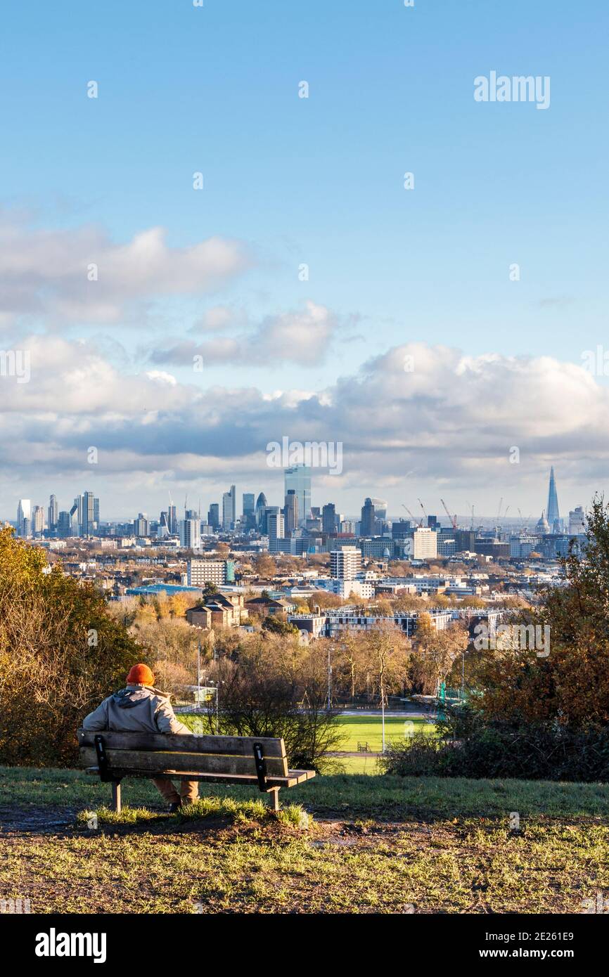 Ein Mann, der auf einer Bank sitzt und während der Sperre des Coronavirus-Pandemievirus, London, Großbritannien, den Blick über die Stadt vom Parliament Hill aus betrachtet Stockfoto