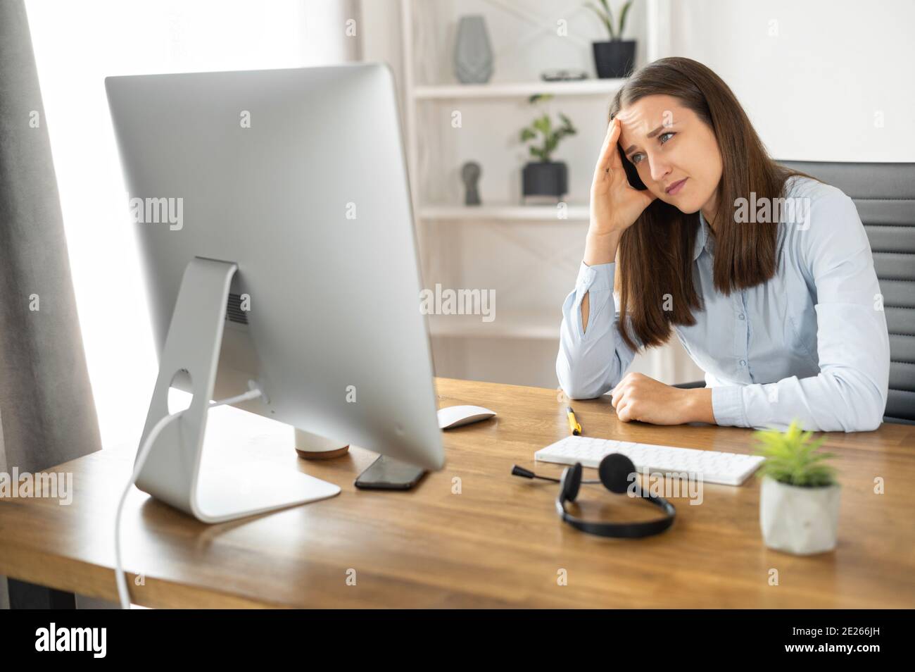Eine junge Frau benutzt im Büro einen PC Stockfoto