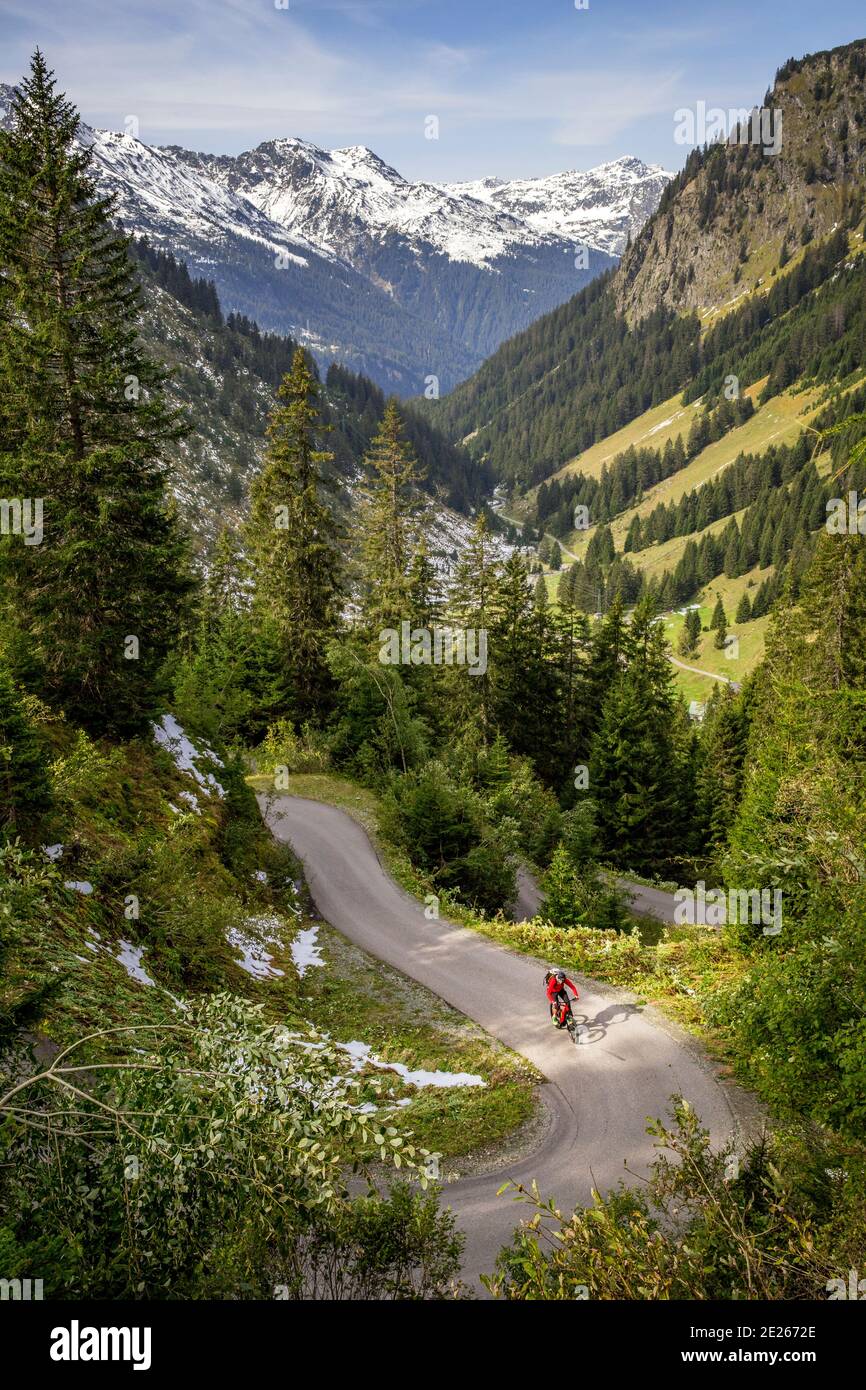 Mountainbiker auf aufsteigender kurvenreicher Straße mit Kehren in der Montafon-Region im Herbst, Vorarlberg, Österreich Stockfoto