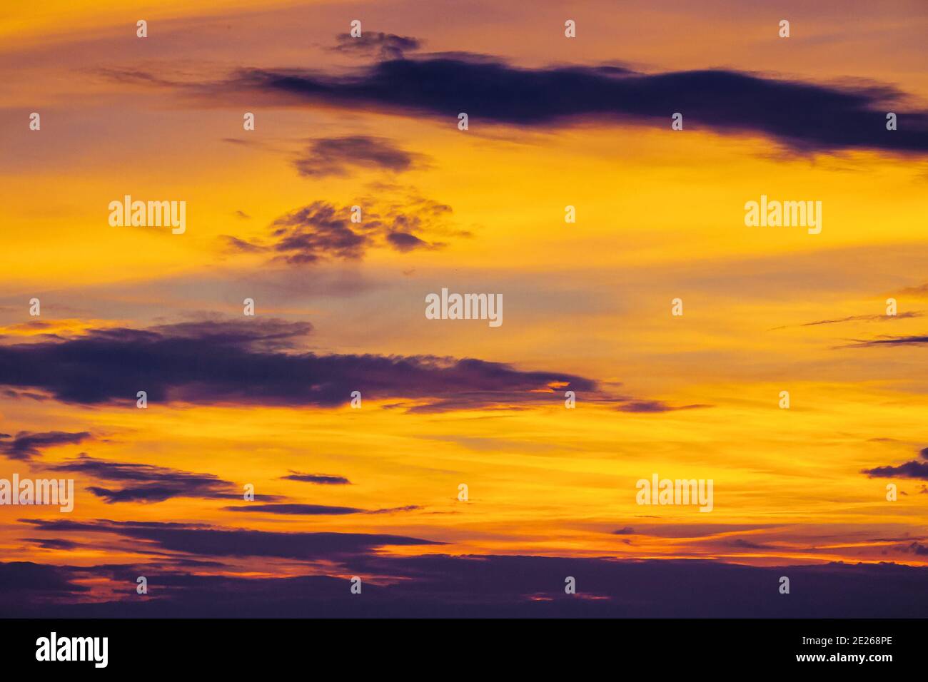 Dunkle Wolken am glühenden Himmel bei Sonnenuntergang. Dramatische Naturkulisse am windigen Wetter am Abend Stockfoto