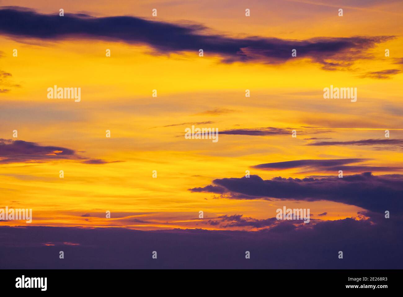 Dunkle Wolken am glühenden Himmel bei Sonnenuntergang. Dramatische Naturkulisse am windigen Wetter am Abend Stockfoto
