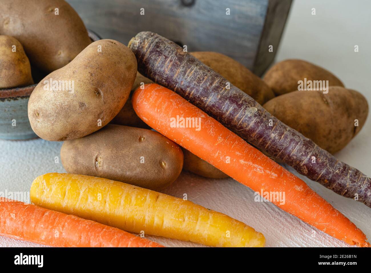 Kartoffeln und Karotten aus nächster Nähe auf weißem Küchentisch Stockfoto