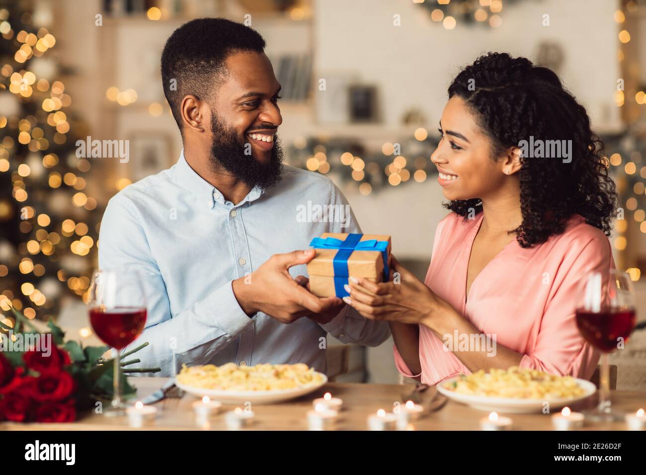 Junger schwarzer Mann, der Geschenke mit seiner glücklichen Frau austauscht Stockfoto